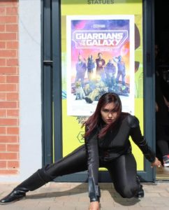 Lauren Maduray strikes a dynamic pose in black tactical gear, mirroring the fearless spirit of The Shadower, her comic book where real people become superheroes.