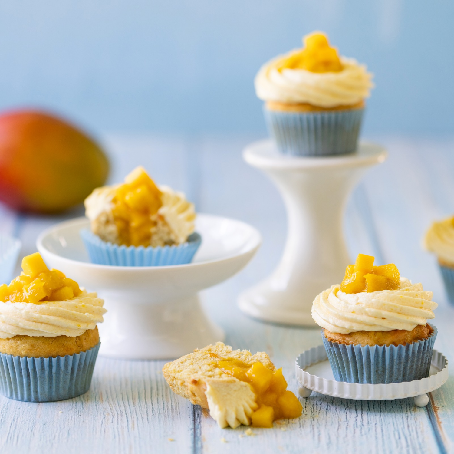 A batch of golden, fluffy Mango cupcakes topped with creamy frosting and fresh mango slices, perfect for Valentine's Day.