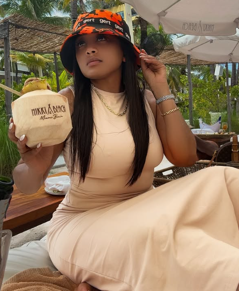 Miss LKG turning heads at Nikki Beach in Miami, rocking a sexy summer dress, a vibrant hat, and sipping on a beachside drink. Picture: Instagram@LeratoKganyago