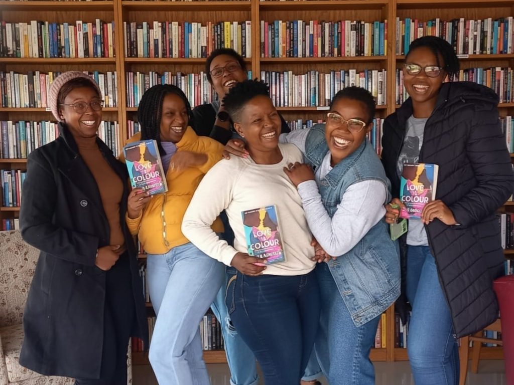 Paballo and her book club members shine with happiness, as they are posing with their books behind a bookshelf. Picture: Supplied