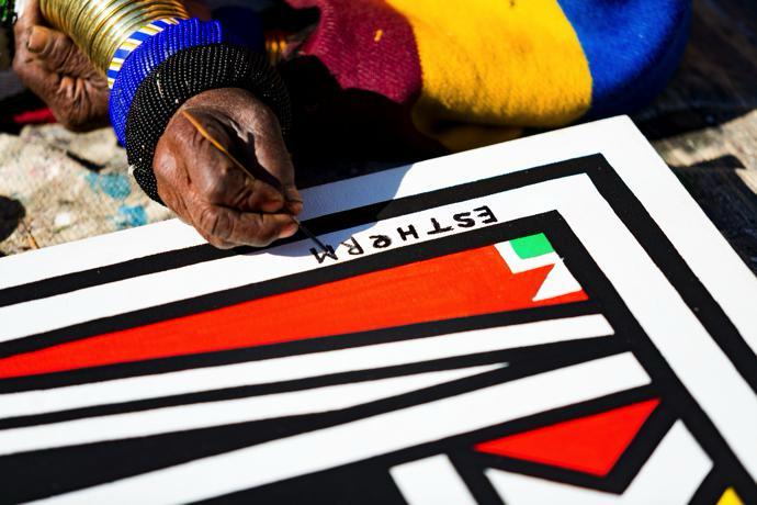 Dr. Ester Mahlangu signing her name on one of her iconic Ndebele artworks. Picture: Supplied