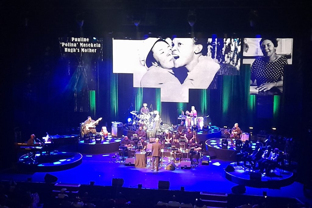 A view of the stage setup, with the band performing and images of Hugh Masekela displayed on screen. Picture: Author's Own