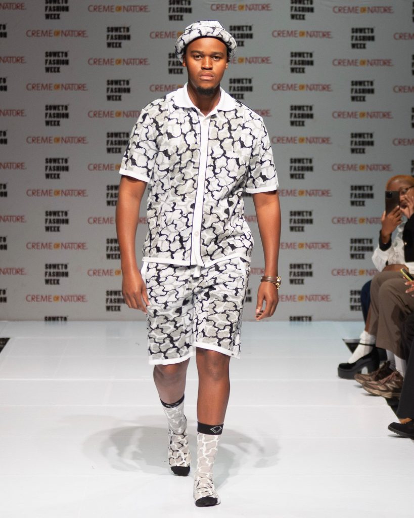 Soweto Fashion Week AW26. Model wearing IDAYIMANI's Crown Black Bucket Hat, Black Button-Up Short-Sleeve Shirt, Black Shorts, and Black Socks. Picture: Supplied